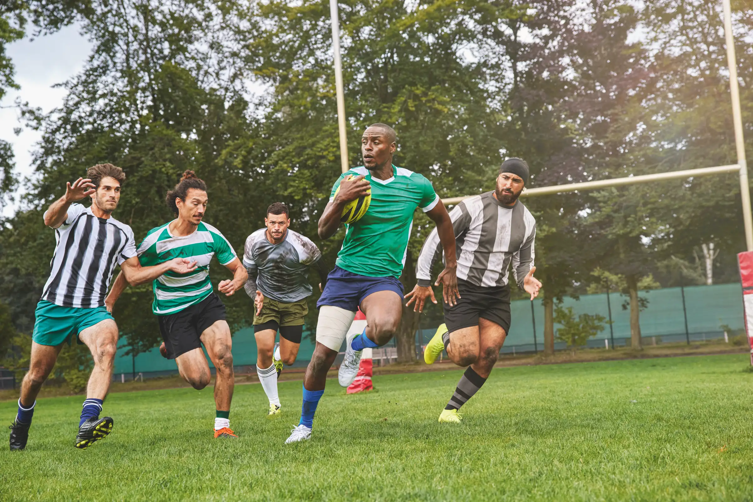 Joueurs de rugby en plein match sur un terrain extérieur, illustrant l’utilisation des bandes Tensoplast® pour le soutien musculaire et la prévention des blessures sportives.